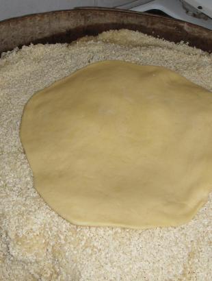 3. Τοποθετούμε την πίτα πάνω στο σησάμι, για να κολλήσει στην κάτω επιφάνεια.