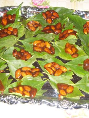 4. Προσθέτουμε τα αμύγδαλα στην καραμέλα και τα τοποθετούμε λίγα-λίγα, με κουτάλι πάνω σε κάθε φύλλο λεμονιάς.