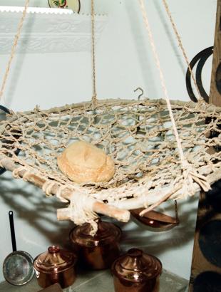 Σιταρένιο ψωμί τοποθετημένο για φύλαξη στην ταπατζιά ή κοφινιά. Πίσω δεξιά διακρίνεται το κουπποσάνιδο.