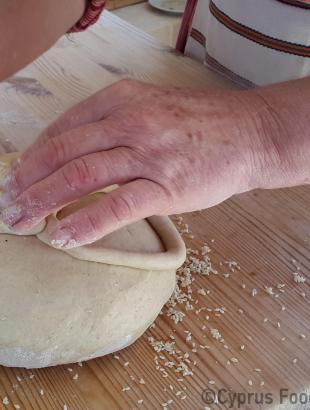 Διακόσμηση της γεννόπιττας. Με λωρίδα ζυμαριού σχηματίζεται σταυρός ή τετράφυλλη μαργαρίτα. Λετύμπου 2016.