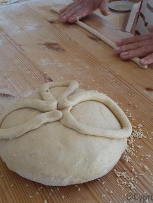 Διακόσμηση της γεννόπιττας. Με λωρίδα ζυμαριού σχηματίζεται σταυρός ή τετράφυλλη μαργαρίτα. Λετύμπου 2016.