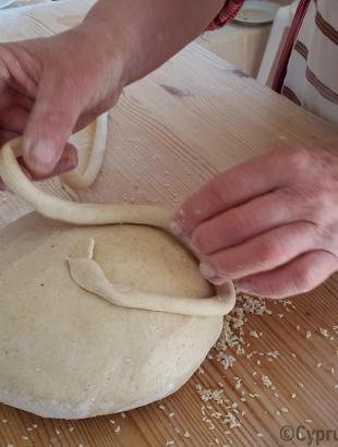 Διακόσμηση της γεννόπιττας. Με λωρίδα ζυμαριού σχηματίζεται σταυρός ή τετράφυλλη μαργαρίτα. Λετύμπου 2016.